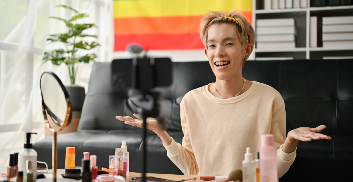 A person smiling in front of a Pride flag