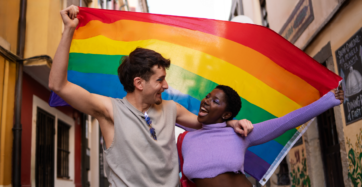 A couple laughing together while holding a Pride flag